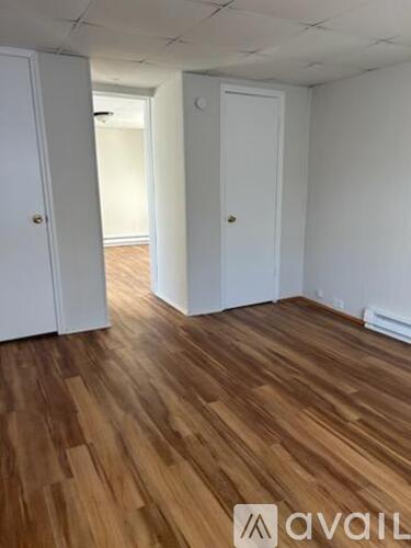 A room with wooden flooring and white walls.