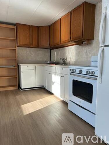 A kitchen with white appliances and wooden cabinets.
