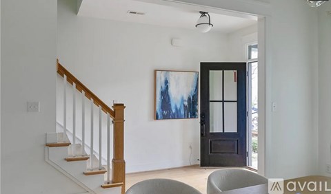 A living room with a staircase and a painting on the wall.