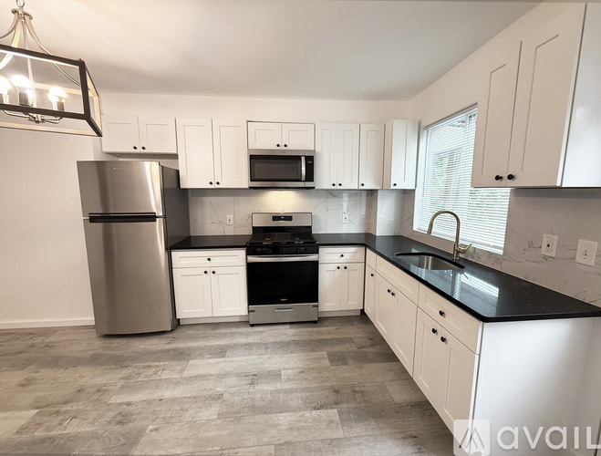 A kitchen with white cabinets and a black countertop.