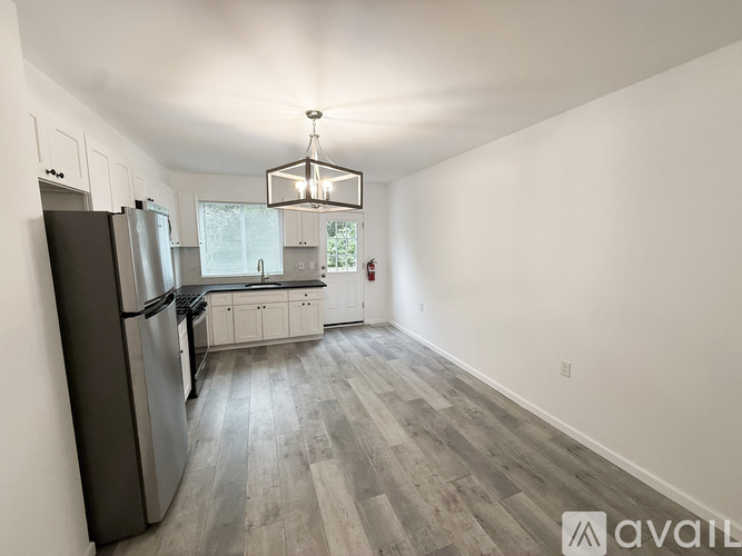 A kitchen with a refrigerator, cabinets, and a dining table.