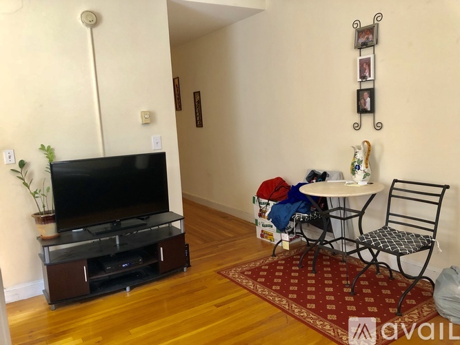 A living room with a TV, a table with chairs, and a plant.