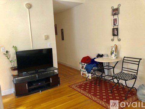 A living room with a TV, a table with chairs, and a plant.