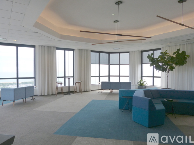 A spacious room with a blue couch and a large window overlooking the city.