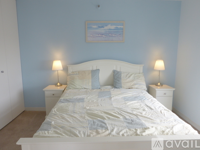 A bedroom with a large bed and two lamps on either side of the bed.