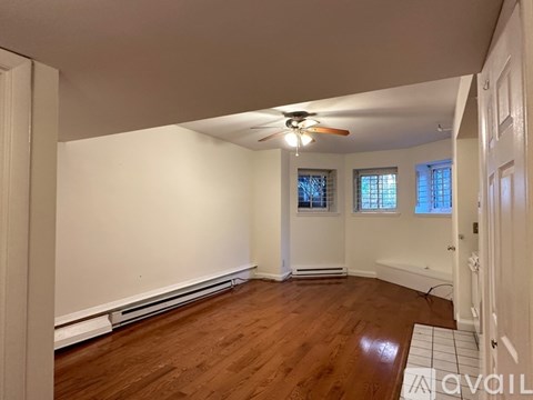 A room with a ceiling fan and wooden flooring.