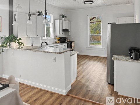 A kitchen with white cabinets and a wooden floor.