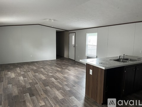 A kitchen with a sink and a counter with a wood grain pattern on the floor.