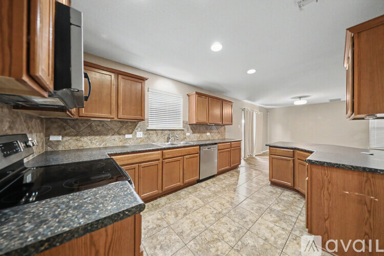 A kitchen with wooden cabinets and black countertops.