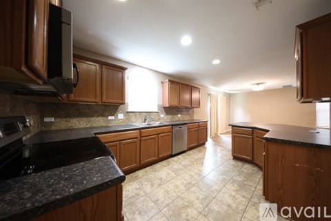 A kitchen with wooden cabinets and black countertops.