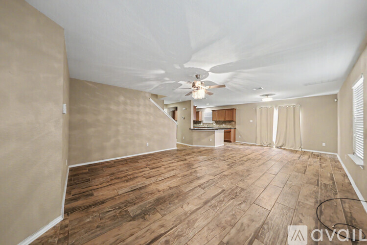 A spacious room with wooden flooring and a ceiling fan.