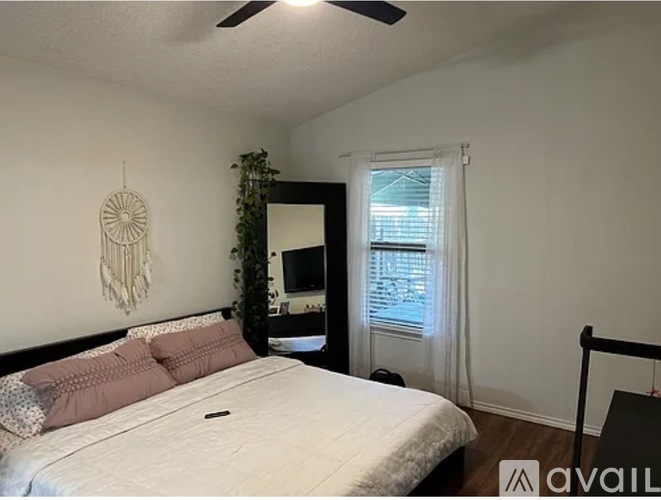 A bedroom with a bed, a ceiling fan, and a dreamcatcher hanging on the wall.