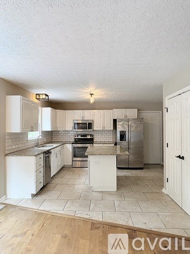 A kitchen with white cabinets and a tiled backsplash.