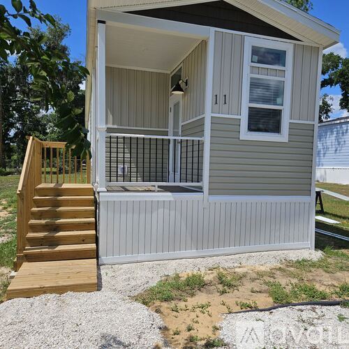 A small house with a porch and a staircase leading to the entrance.