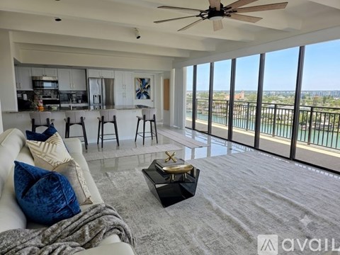 A bedroom with a large bed, a ceiling fan, and a view of the city.
