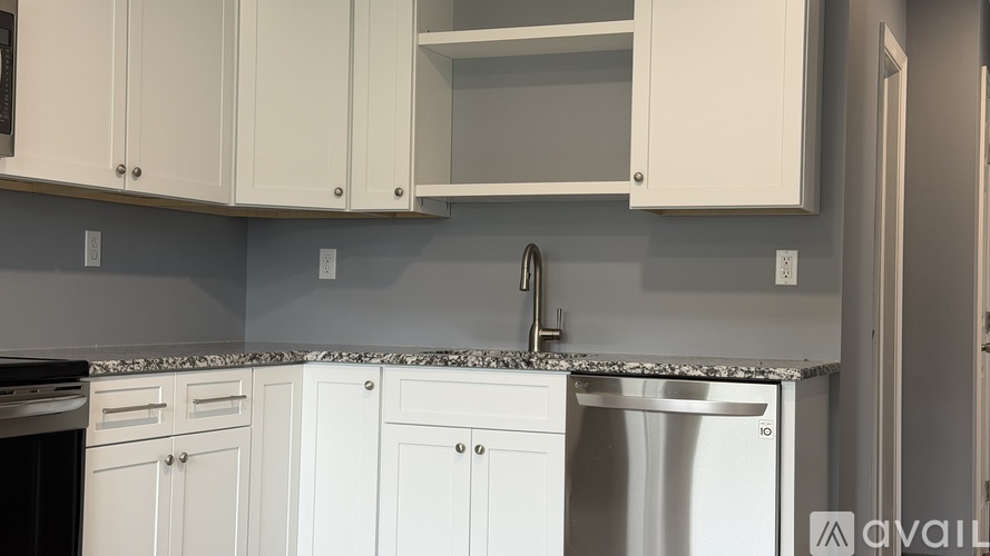 A kitchen with white cabinets and a granite countertop.