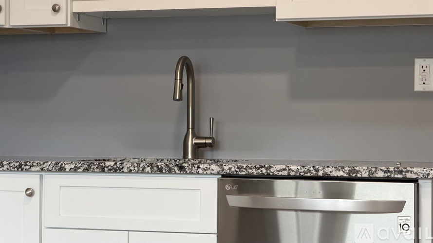 A kitchen sink with a granite counter top and a white cabinet.