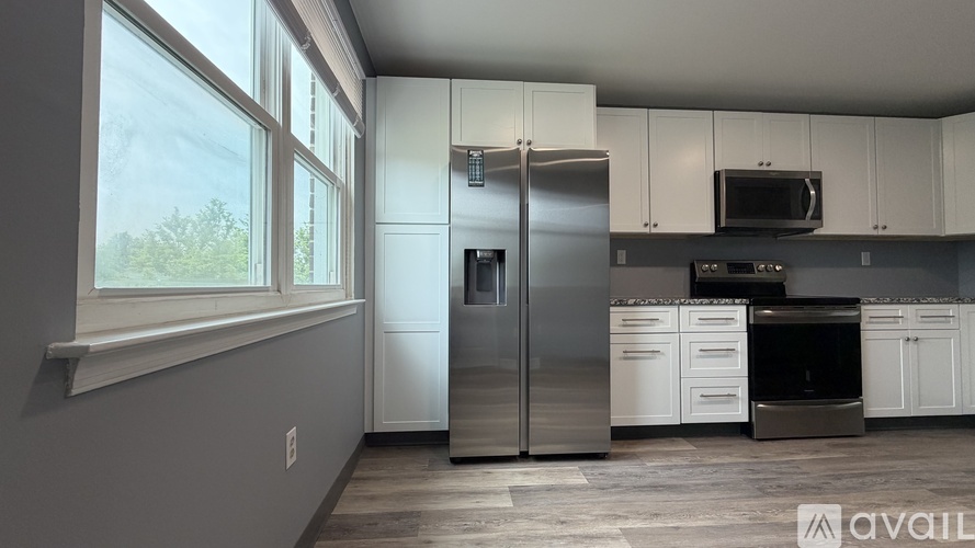 A kitchen with white cabinets and stainless steel appliances is available for rent.