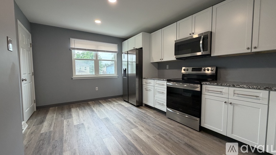 A kitchen with white cabinets and a grey floor.