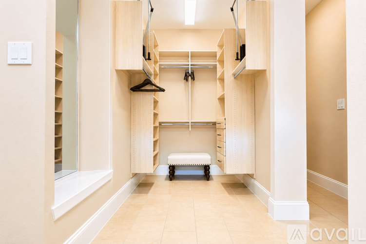 A spacious walk-in closet with wooden shelves and drawers.