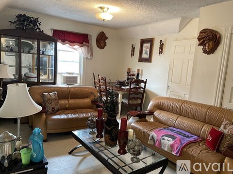 A living room with a brown leather couch and a glass coffee table.