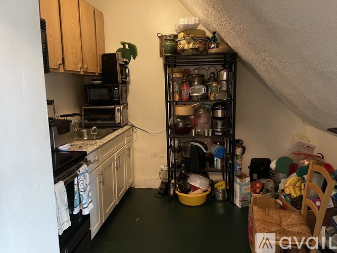 A kitchen with a green floor and a shelf with many pots and pans.