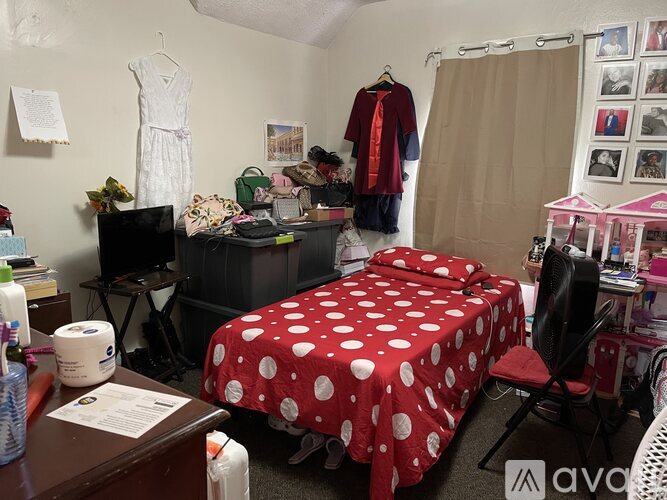 A bedroom with a bed covered in a red and white polka dot comforter.