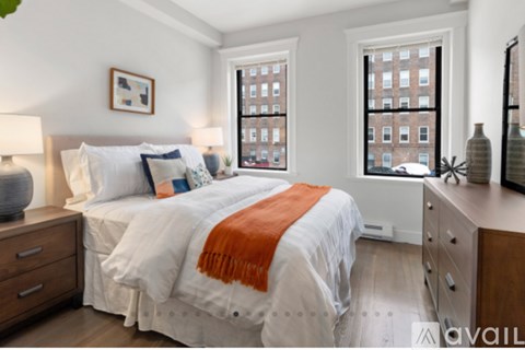 A bedroom with a large bed and a window overlooking a city street.
