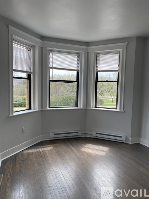 A room with wooden floors and three windows.