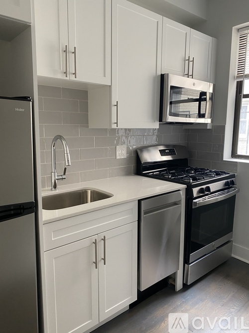 A kitchen with white cabinets and a stainless steel refrigerator.