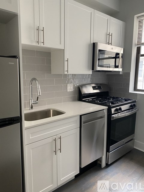 A kitchen with white cabinets and a stainless steel refrigerator.