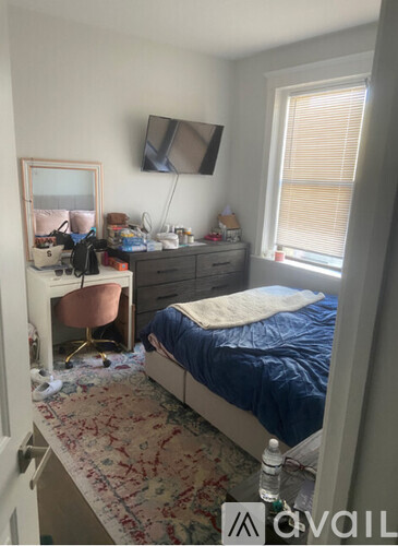 A bedroom with a bed, desk, chair, and a mirror on the wall.