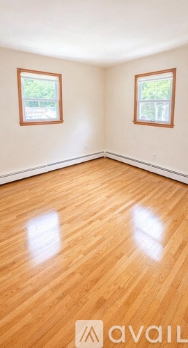 A room with wooden floors and two windows.