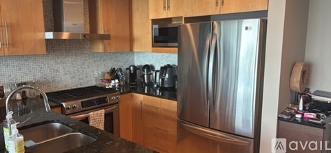 A kitchen with a stainless steel refrigerator and wooden cabinets.