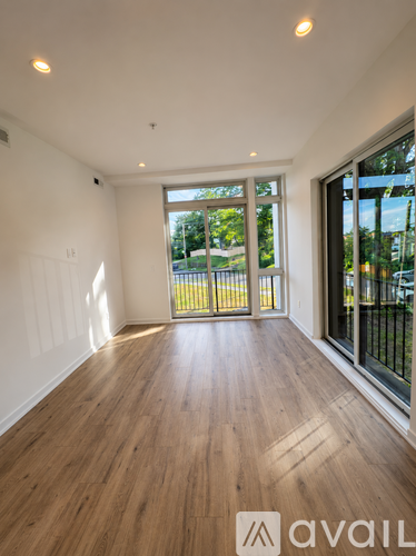 A room with wooden floors and a view of a fenced area outside through the glass doors.