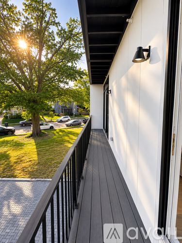 A balcony with a black railing and a tree in the background.