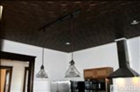 A kitchen with a dark ceiling and hanging lights.