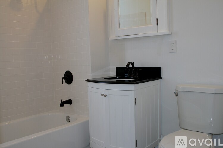 A white bathroom with a black counter top and a white tub.