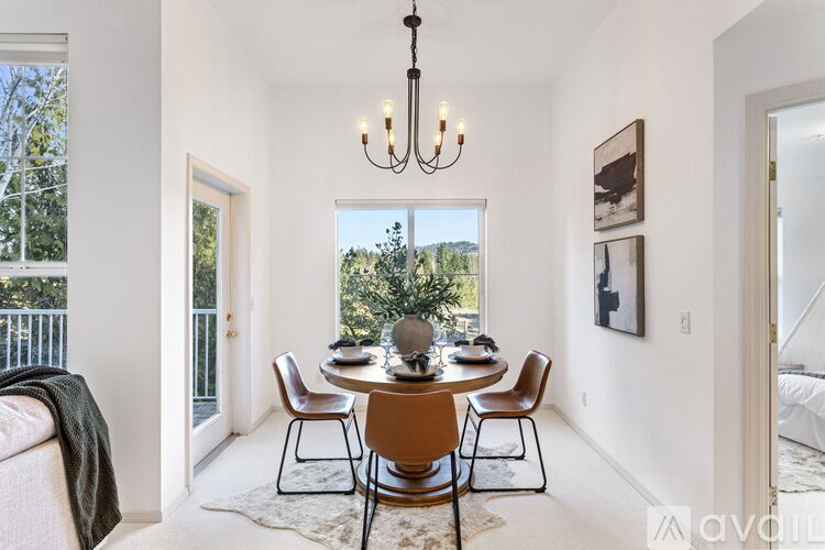 A dining room with a table set for six and a chandelier hanging from the ceiling.