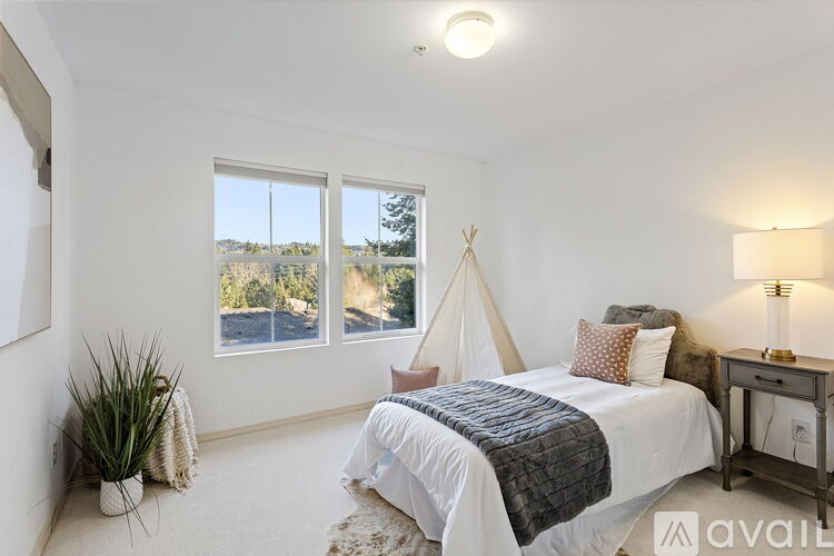 A bedroom with a bed, a lamp, and a potted plant.
