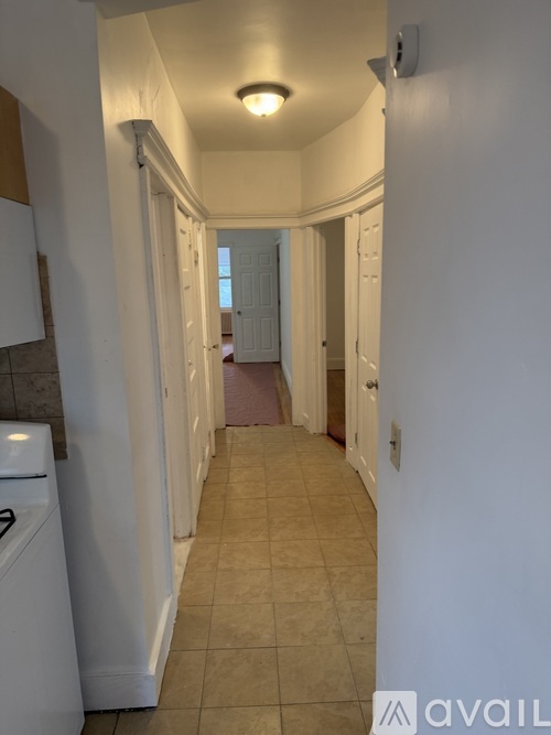A hallway with a tiled floor and white walls.