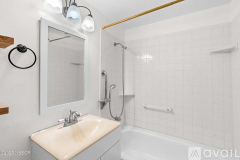 A bathroom with a white sink and a white tiled shower.