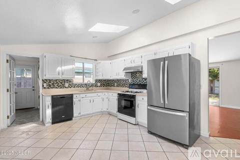 A kitchen with white cabinets and a stainless steel refrigerator.