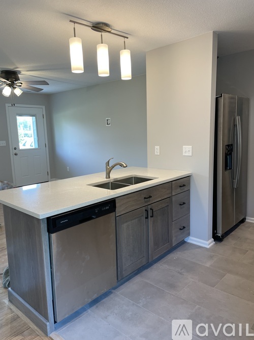 A kitchen with a sink, dishwasher and refrigerator.