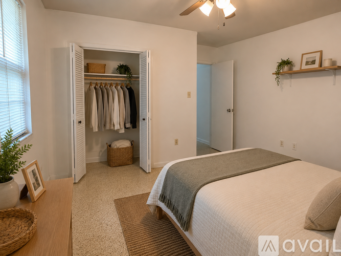 A bedroom with a large bed and a closet with clothes hanging.