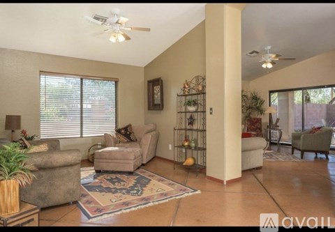 A living room with a rug on the floor and a fan on the ceiling.