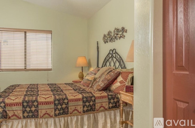 A bedroom with a patterned bedspread and a wall hanging.