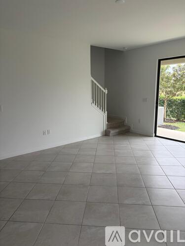 A spacious room with a tiled floor and a staircase leading to another level.