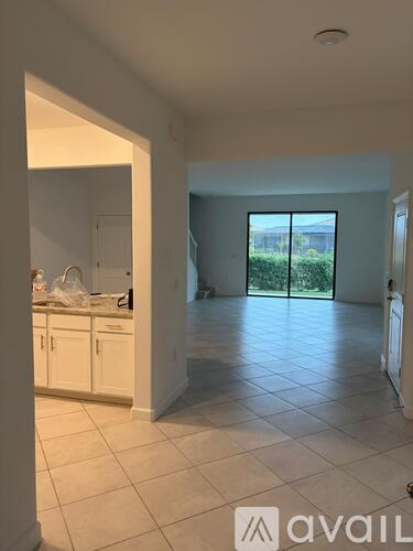 A room with a kitchen area and a sliding glass door leading to a backyard.