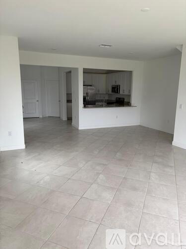 A spacious empty room with tiled flooring and white walls.